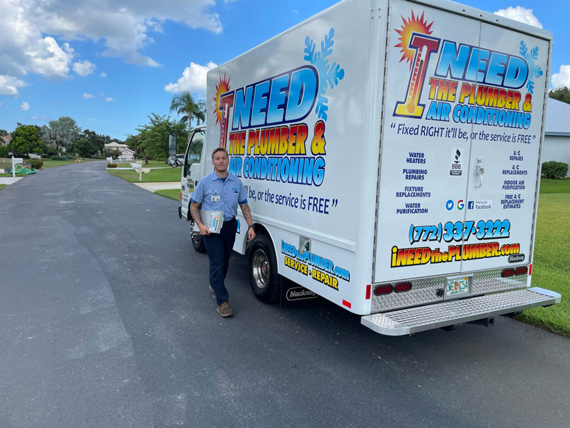 Happy service tech next to I Need the Plumber and AC truck